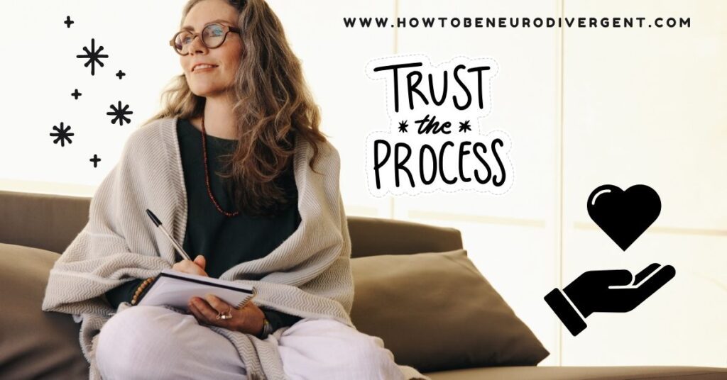 A middle-aged woman wearing glasses sits staring off into the distance with a soft smile. She has a journal and a pen in her lap. There is the doodle image of a hand holding a heart, some sparkles, and the words "trust the process" overlaid on the photo. How to Set Intentions When You Don't Trust Yourself Anymore